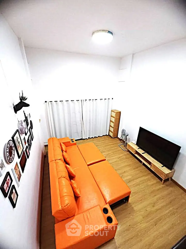 Modern living room with vibrant orange sofa and sleek TV setup, perfect for cozy family gatherings.