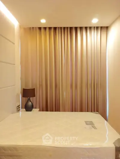 Cozy bedroom with elegant curtains and modern lamp, perfect for relaxation.