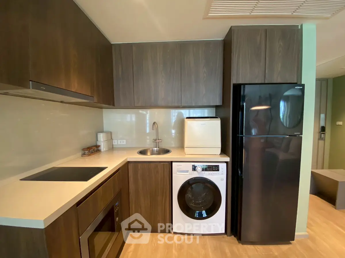 Modern kitchen with sleek cabinetry, built-in appliances, and washing machine in a compact layout.