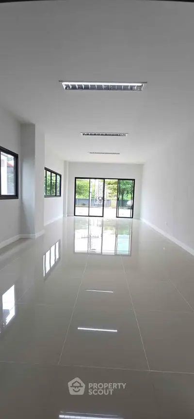 Spacious modern interior with large windows and glossy tiled floors, perfect for versatile living or office space.