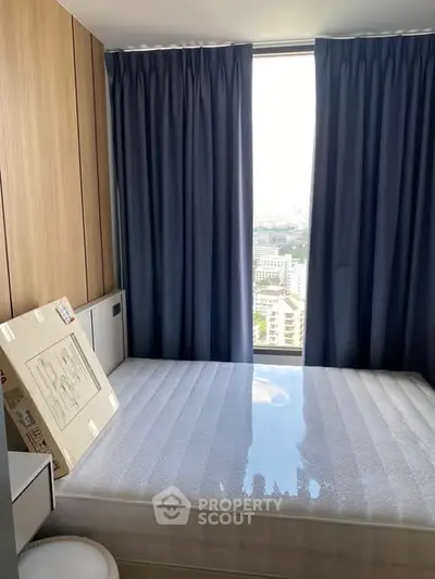 Modern bedroom with large window and city view, featuring sleek wooden paneling and blue curtains.