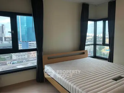 Modern bedroom with large windows offering stunning city views in a high-rise apartment.