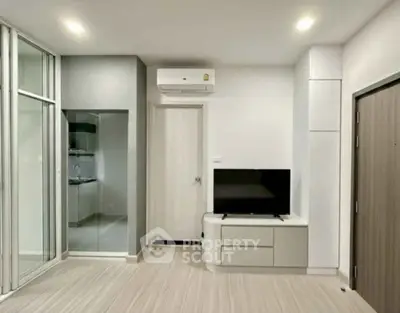 Modern living room with sleek design, featuring a TV unit and air conditioning, adjacent to a glass-enclosed kitchen.