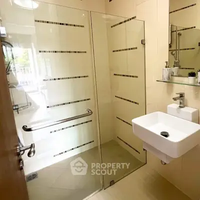 Modern bathroom with glass shower enclosure and sleek fixtures in a bright, contemporary design.