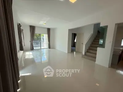 Spacious modern living room with large windows and staircase, perfect for family gatherings.