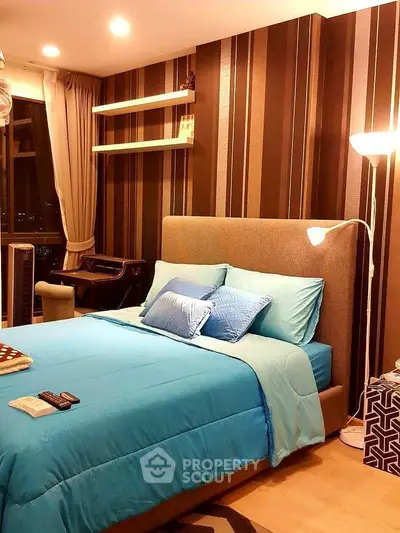 Cozy bedroom with modern decor and large window view, featuring stylish striped wallpaper and ambient lighting.