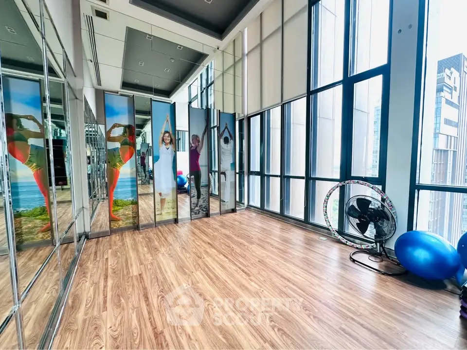 Spacious fitness room with mirrored walls and large windows in modern building