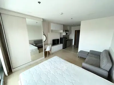 Modern studio apartment with sleek furniture and open layout, featuring a cozy living area and compact kitchen.