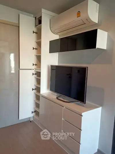Modern living room with sleek storage and mounted TV, featuring minimalist design and air conditioning.