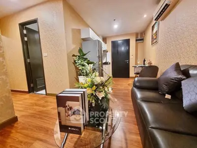Modern living room with elegant decor and open kitchen layout, featuring stylish furniture and warm lighting.