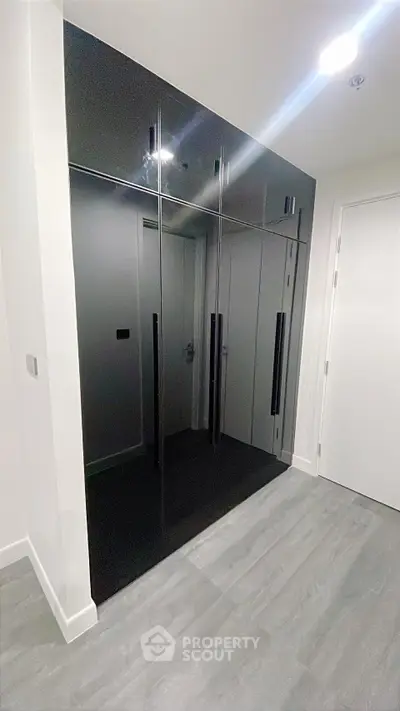Sleek modern hallway with glossy black built-in storage cabinets and elegant flooring.