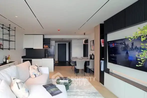 Modern open-layout living room with sleek design and large TV, perfect for entertainment and relaxation.