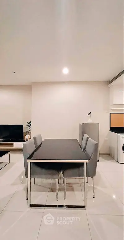 Modern dining area with sleek table and chairs, adjacent to a cozy living space and stylish kitchen.