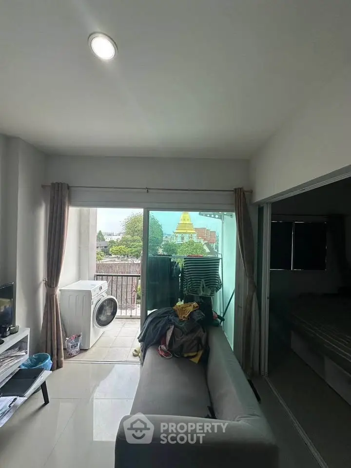 Cozy living room with balcony view and washing machine, perfect for urban living.