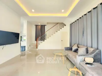 Modern living room with sleek staircase and stylish furniture in a bright, open space.