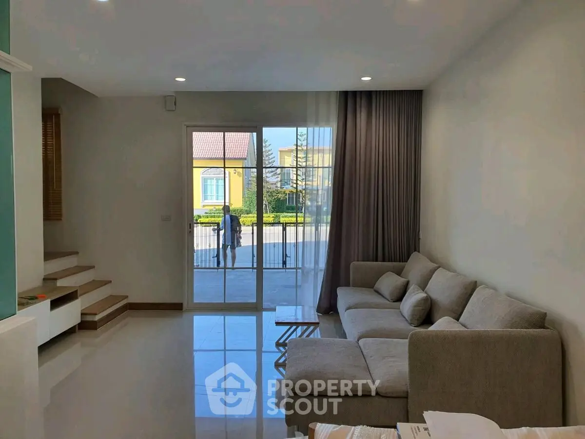 Spacious living room with modern sofa and large window offering natural light