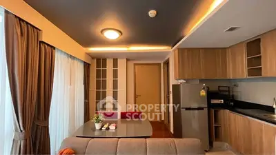 Modern living room with open kitchen, stylish lighting, and cozy dining area.