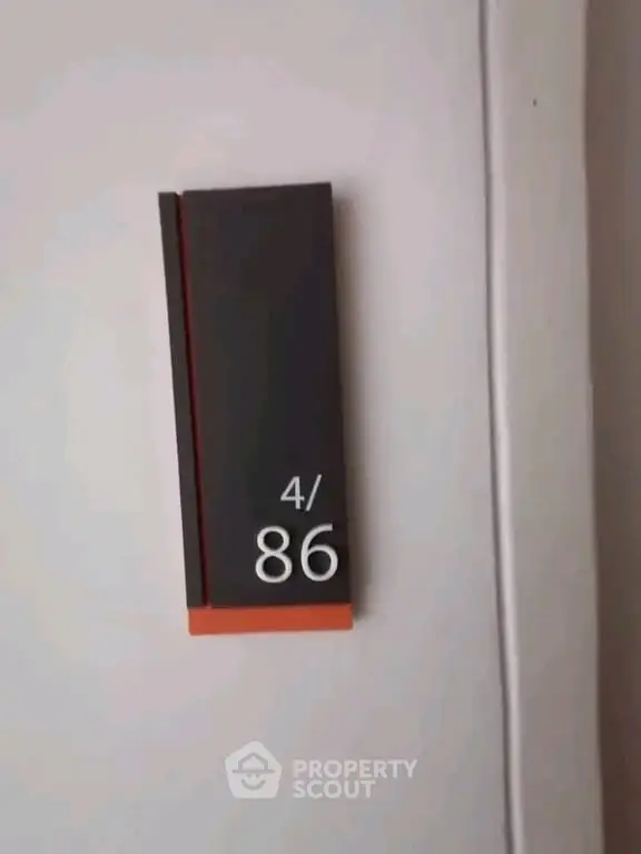 Modern apartment number sign on a white wall, indicating unit 4/86.