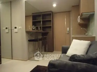 Cozy living room with modern kitchenette and mirrored wall in a compact apartment.