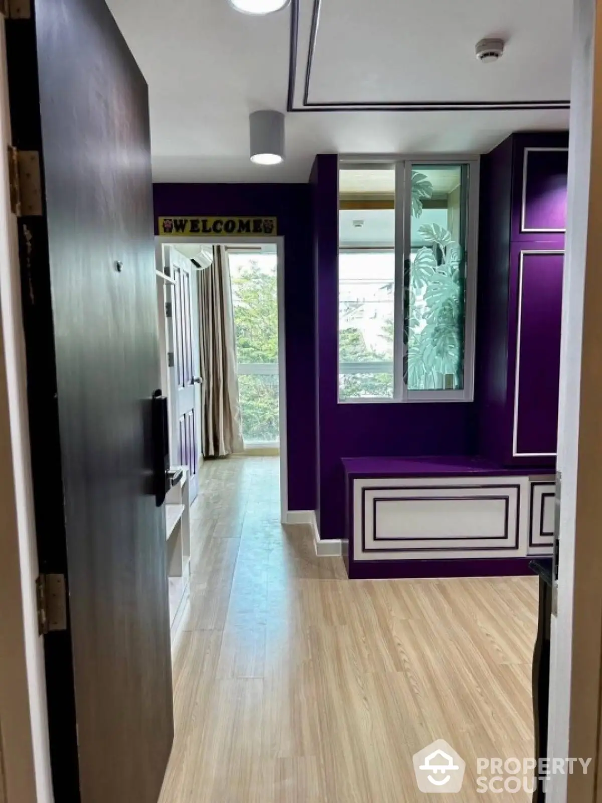 Stylish modern apartment entrance with vibrant purple accents and wooden flooring.