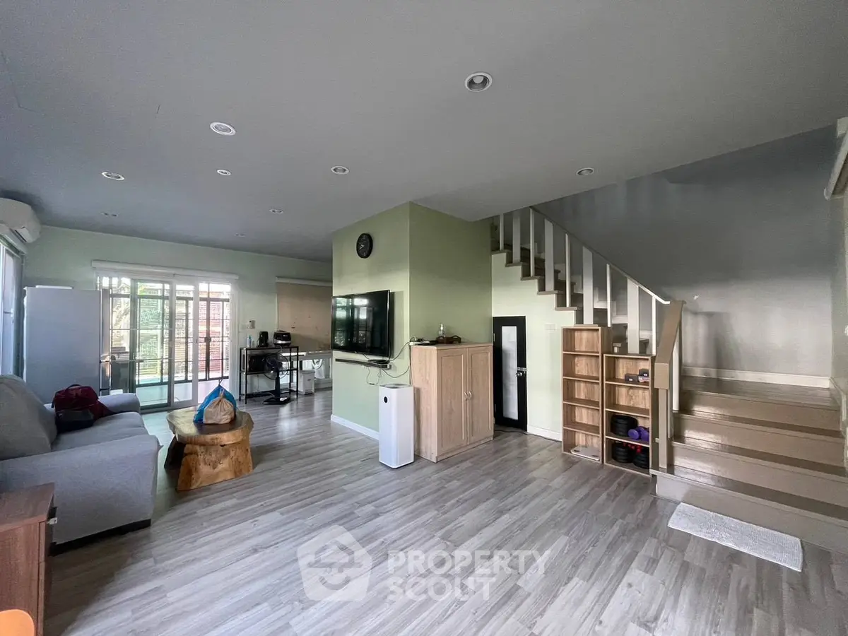 Spacious modern living room with stylish decor and open layout, featuring a staircase and natural light.