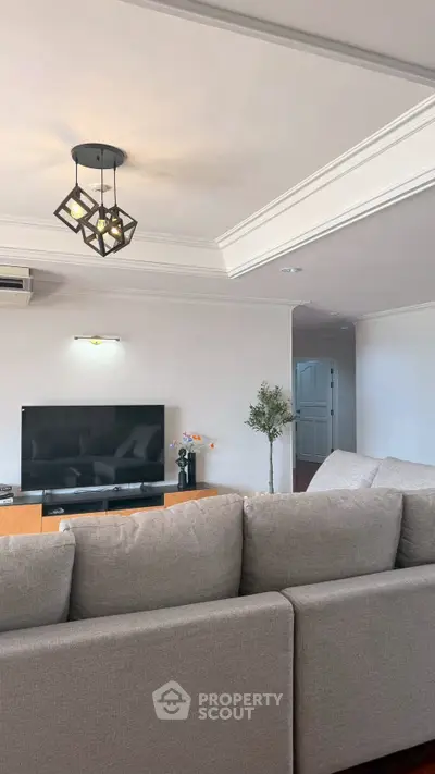 Spacious living room with modern decor and large TV, perfect for relaxation and entertainment.