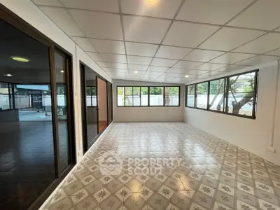 Spacious sunlit room with large windows and patterned tile flooring