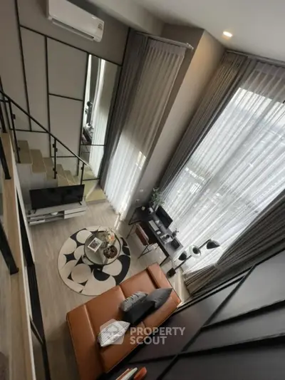 Modern loft-style living room with high ceilings and large windows