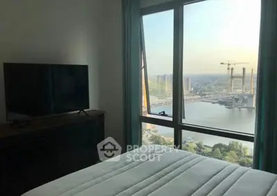 Bedroom with stunning river view and large window, featuring a TV and cozy bed.