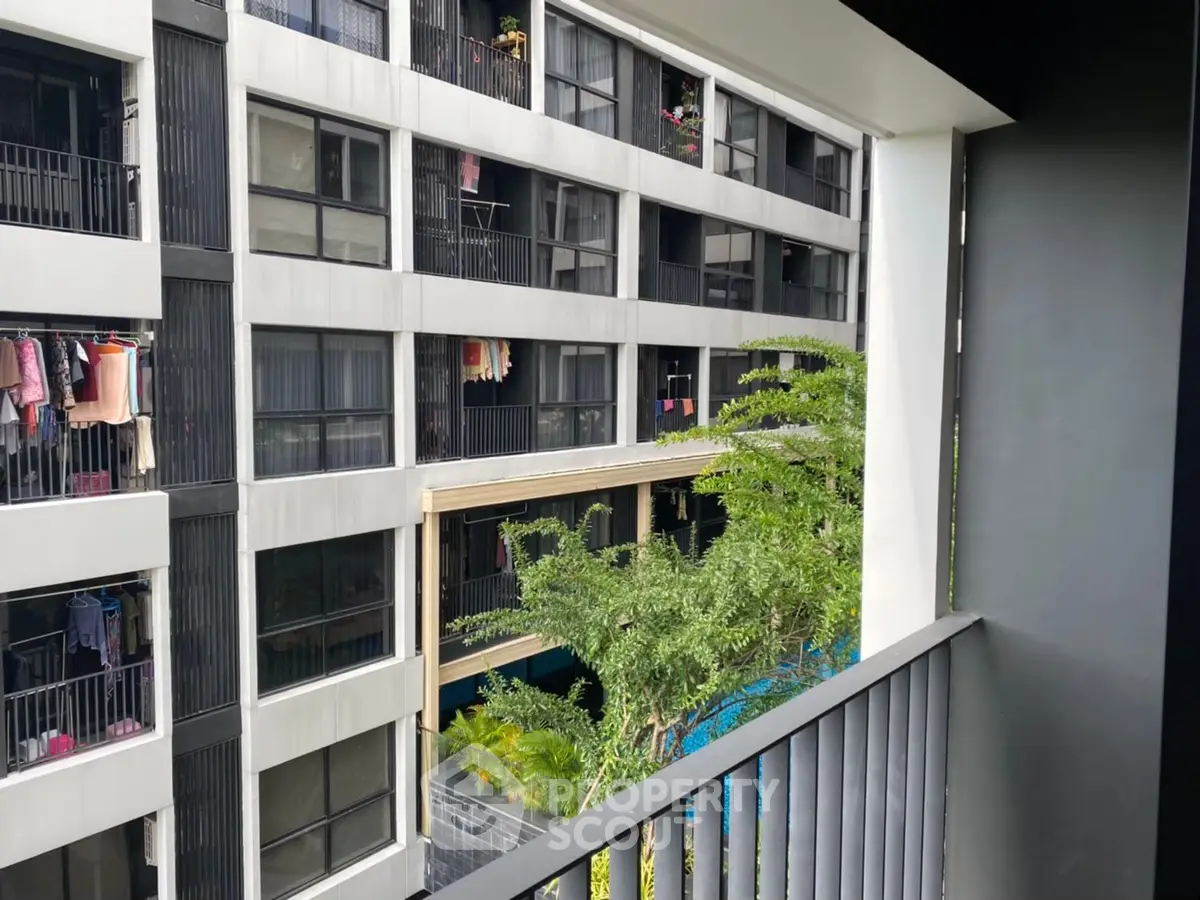 Modern apartment building with balconies and lush greenery view.