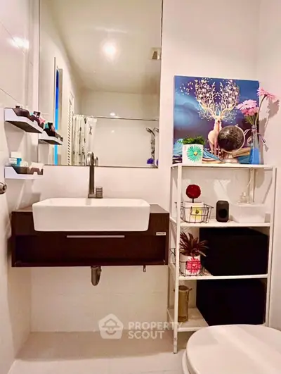 Modern bathroom with sleek sink, wall-mounted shelves, and decorative art piece, offering a stylish and functional space.