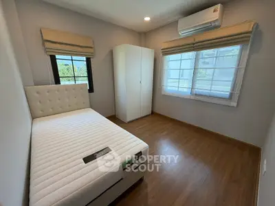 Modern bedroom with large windows and air conditioning, featuring a comfortable bed and sleek wooden flooring.