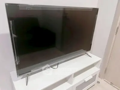 Modern living room with sleek TV on stylish white stand, perfect for entertainment.