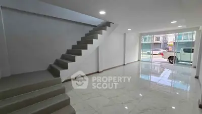 Spacious modern interior with sleek staircase and large window, ideal for urban living.