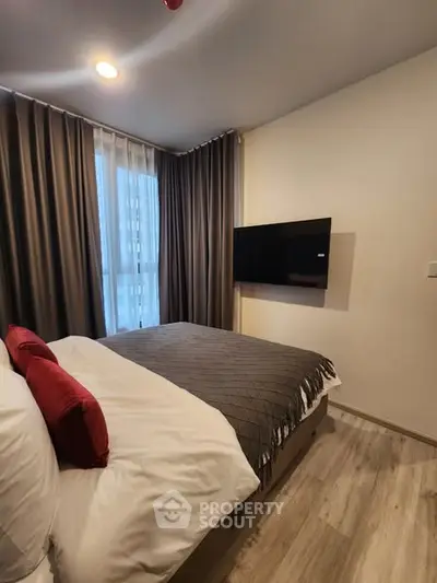 Cozy bedroom with modern decor and wall-mounted TV in stylish apartment.