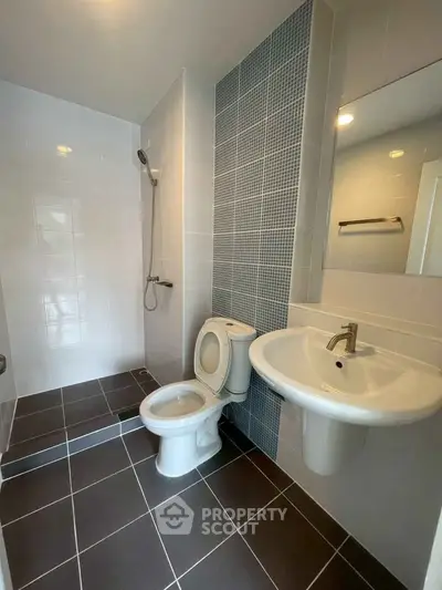 Modern bathroom with sleek design and tiled walls, featuring a shower and contemporary fixtures.