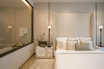 Luxurious bedroom with elegant decor and large glass partition overlooking bathroom.