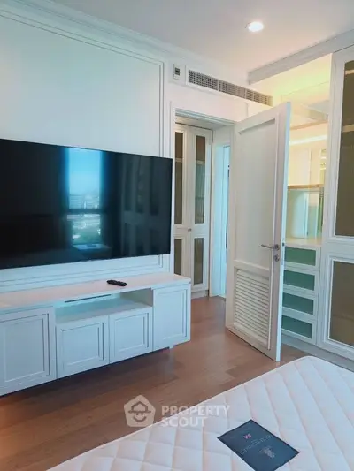 Modern bedroom with large TV and stylish decor in a luxury apartment.