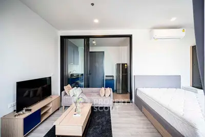 Modern studio apartment with open layout, featuring a cozy living area, sleek kitchen, and comfortable bed.