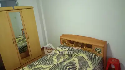 Cozy bedroom with wooden wardrobe and unique bedspread in a compact space.