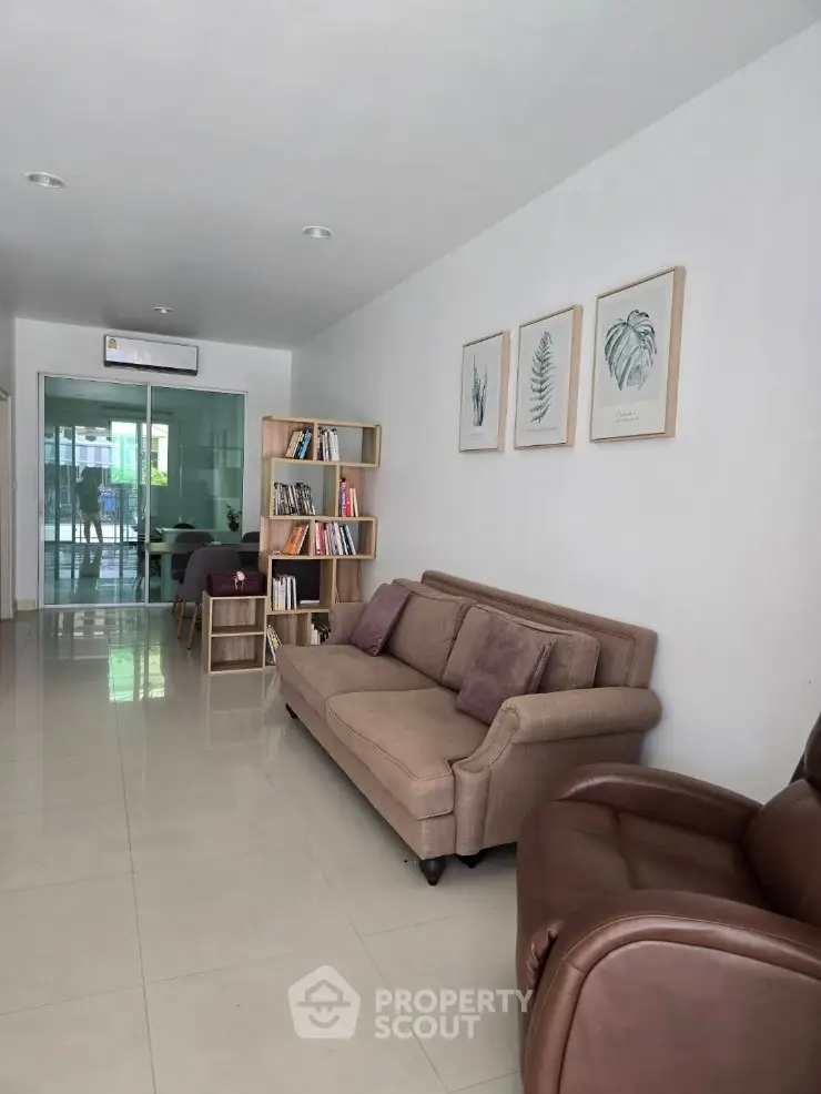 Modern living room with sleek furniture and bookshelf, featuring a cozy ambiance and contemporary decor.