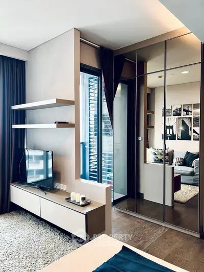 Modern living room with sleek design, featuring a TV, stylish shelves, and a cozy seating area.
