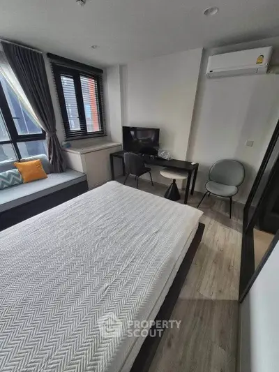 Modern bedroom with stylish decor, featuring a cozy bed, desk, and large window for natural light.