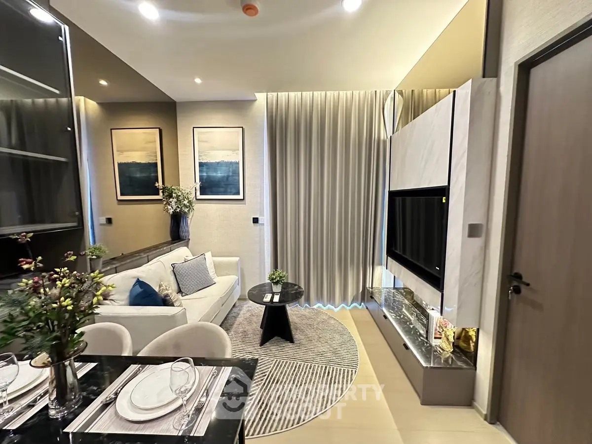 Modern living room with elegant decor and stylish furniture, featuring a cozy sofa and a sleek TV setup.