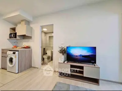 Modern studio apartment with open kitchen and cozy living area featuring a washing machine and TV.
