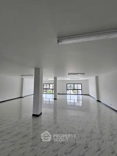 Spacious open-plan interior with large windows and modern lighting, ideal for versatile use.