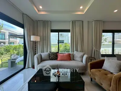 Modern living room with stylish furniture and large windows overlooking a garden.