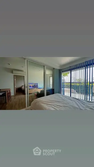 Spacious bedroom with large windows and modern decor, offering a serene view.