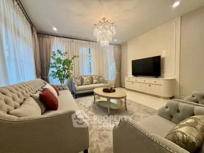 Elegant living room with plush sofas, chandelier, and large TV, perfect for luxury living.