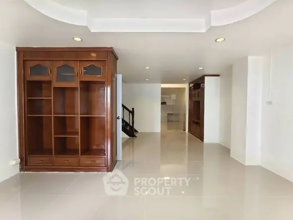 Spacious living room with elegant wooden shelving and modern tile flooring.